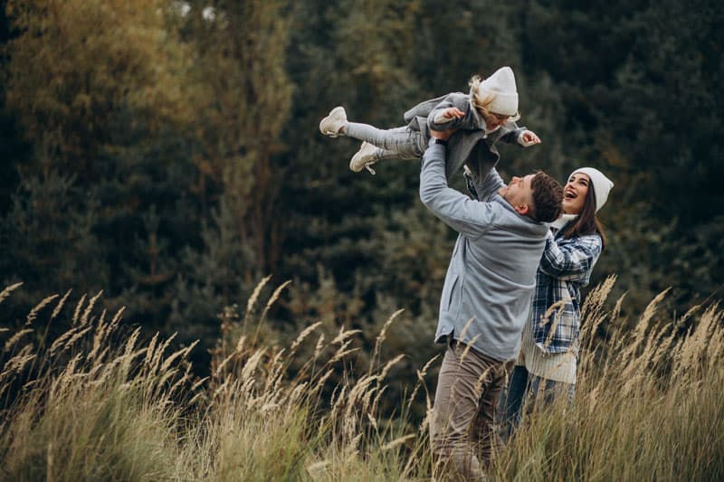 A family with a little daughter together outdoors in autumnal weather